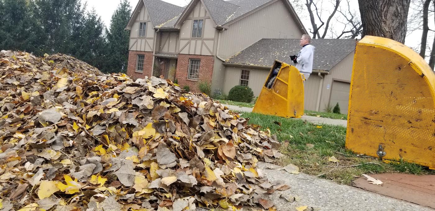 Leaf vacuum rig beside a large curbside pile of leaves